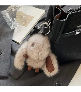 Detail of cute brown plush bunny charm with metal clasp on black pebbled leather bag