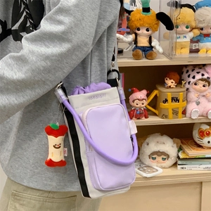 Detail of purple and grey crossbody phone bag with woven strap and plush charm