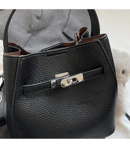 Detail of silver twist-lock closure on black pebble leather bucket bag with fur charm