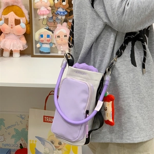Detail of crossbody bag featuring drawstring closure, adjustable strap and plush charm
