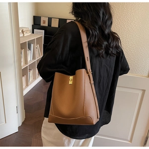 Detailansicht der braunen Leder-Eimertasche mit goldener Schließe und Litschistruktur