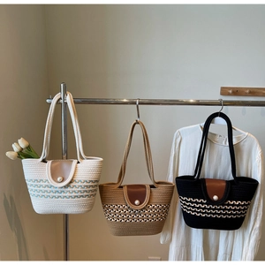 Detailed view of woven tote bags featuring a pearl clasp and sleek leather flap closure