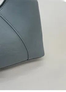 Dettaglio ravvicinato della borsa in pelle azzurra con trama fine e cuciture curate