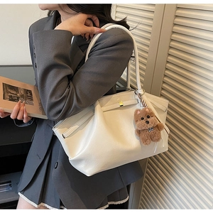 White minimalist tote bag with plush bear charm worn with a grey blazer outfit