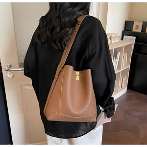 Detailansicht der braunen Lederbeuteltasche mit goldenem Schloss an einem Modell