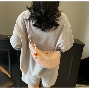 Pink woven dumpling crossbody bag with knot strap and amber charm pendant