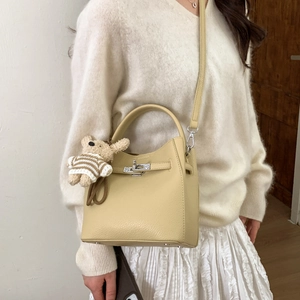 Detail of cream bucket bag with silver twist lock and cute teddy bear charm on handle