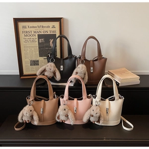 Detail of five leather bucket bags in various colors with silver hardware and rabbit charms