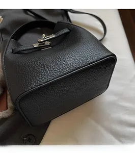 Detail of black litchi grain leather texture and silver buckle on bucket handbag