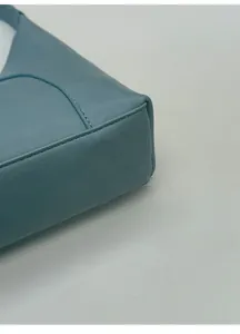 Dettaglio della base ampia di una borsa a tracolla in pelle blu con trama litchi