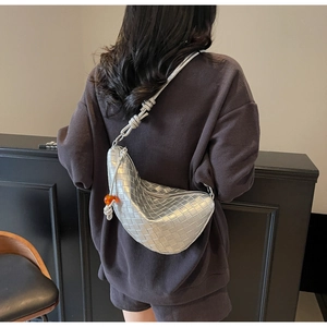 Détails du sac tressé argenté avec perle orange et nœud décoratif sur la bandoulière