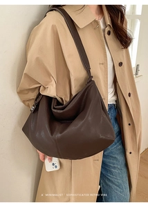 Deep brown leather hobo bag styled with a trench coat for a minimalist retro aesthetic