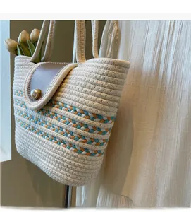 Close-up of woven cotton tote bag with pearl buckle and orange-blue stripe details
