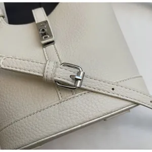 Detail of off-white pebbled leather handbag with adjustable strap and silver metal buckle