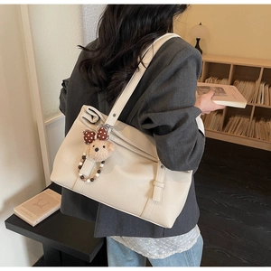 Detail of off-white lychee pattern leather tote bag with a cute brown bear charm