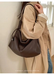 Close-up of the knotted shoulder strap and branded tag on this large brown hobo bag