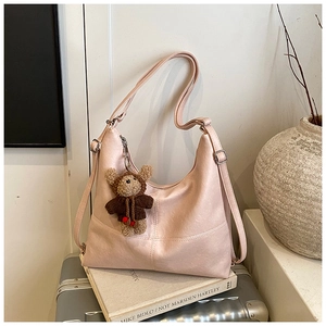 Close-up of pink faux leather tote bag with crossbody strap and cute teddy bear charm