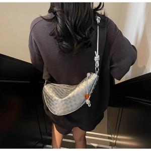 Detail of metallic silver woven dumpling bag with thick knotted strap and orange bead accent