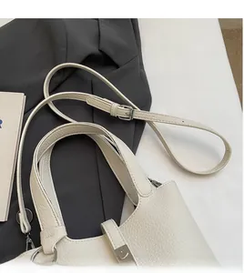 Detailed shot of off-white lychee grain leather handbag with silver hardware and strap