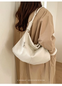 Detail of off-white minimalist hobo bag with knotted strap and soft leather texture