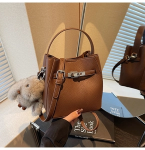 Brown lychee leather bucket bag with metal lock and plush rabbit charm detail