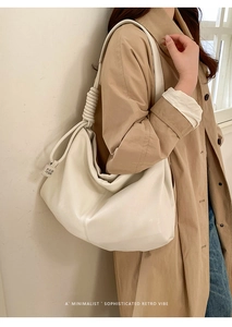 Detail of minimalist cream leather tote bag featuring unique knot-designed shoulder strap