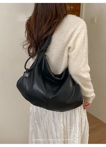 Detail of black large hobo bag featuring knotted shoulder strap and brand tag