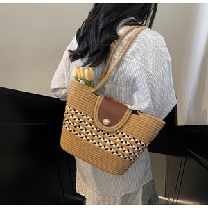 Detail of woven straw tote bag with brown leather flap and pearl button closure