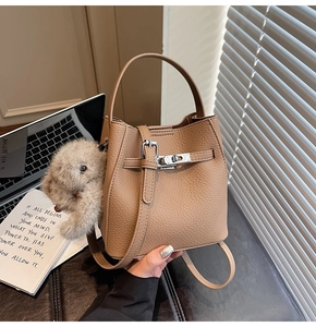 Detail of beige lychee pattern bucket bag with silver lock and plush bunny pendant