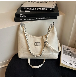 Détail du sac hobo matelassé beige avec chaîne argentée et fermoir à double anneau