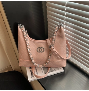 Détail du sac à bandoulière rose matelassé avec chaîne argentée et logo en métal