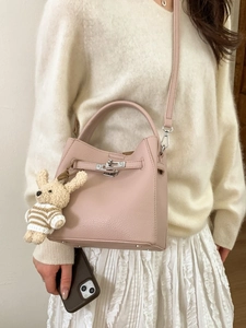 Pink lychee grain leather bucket bag with silver twist lock and plush rabbit pendant