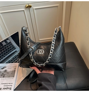 Sac à épaule noir en cuir matelassé avec chaîne argentée posé près d'un ordinateur