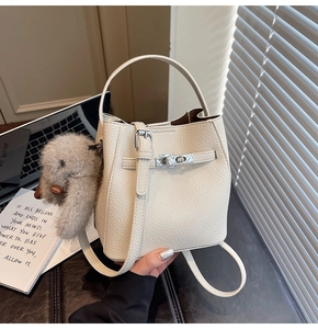 Detail of cream bucket bag with lychee grain leather, silver lock, and rabbit charm