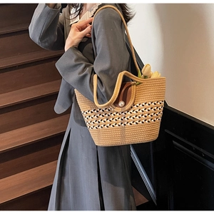 Detail of straw woven beach tote bag with striped pattern and decorative pearl button closure