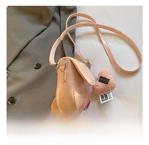 Détail du sac bandoulière rose en similicuir avec quincaillerie argentée et breloque cœur