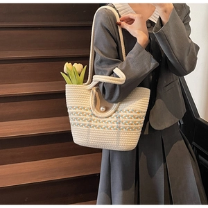 Close-up of straw woven tote bag featuring a pearl clasp and colorful wave pattern