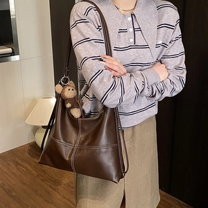 Brown leather large Hobo tote bag with white contrast stitching and bear charm on model