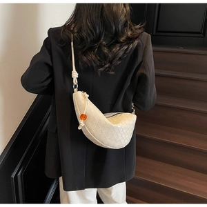 Detailed weave pattern on creamy white crescent bag with orange sphere pendant