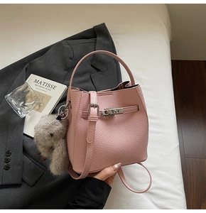 Pink lychee grain bucket bag with silver turn-lock and grey plush rabbit charm