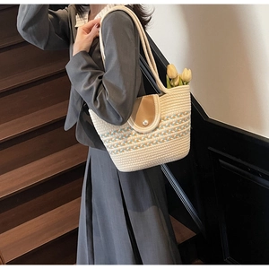 Close-up of straw woven tote with pearl buckle and colorful pattern on leather flap