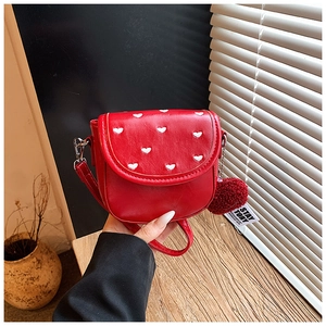 Dettaglio mini borsa rossa a tracolla in ecopelle con ricami a cuore e ciondolo morbido