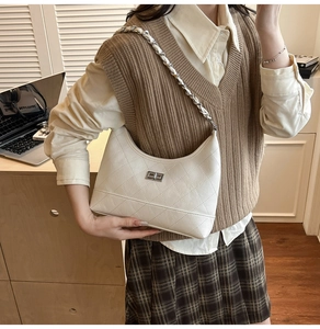 Détail du sac hobo blanc matelassé avec fermoir rotatif et bandoulière en chaîne tissée