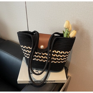 Detail of color-block straw tote with a pearl clasp and brown leather flap cover