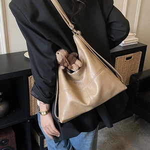 Detail of khaki large tote bag with decorative stitching and brown plush bear charm