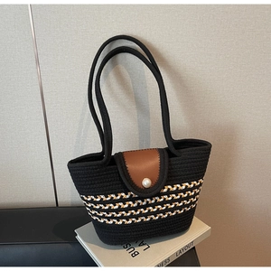 Detail of woven cotton rope beach tote featuring pearl button and brown leather flap closure