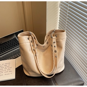 Detail view of large beige PU leather tote bag with stylish silver grommets and rivets
