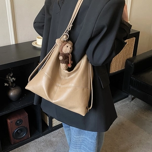 Detail of camel oversized faux leather tote bag with plush bear charm on model