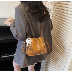 Detail view of mustard yellow ruched shoulder bag with leather strap and metal chain