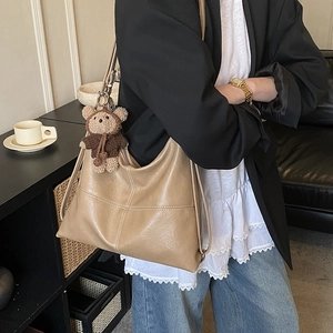 Side view of khaki retro hobo tote bag with visible stitching and cute plush bear charm